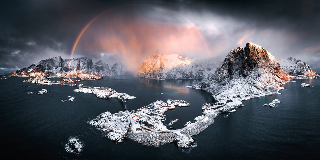 slunce vychází nad bílými horami pokrytými sněhem. duha obklopuje jednu z hor