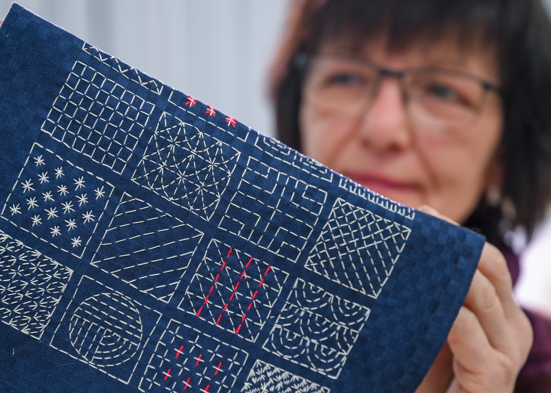 VÝROBA - 13. prosince 2023, Sasko-Anhaltsko, Halle (Saale): V restaurátorské dílně textilu na Univerzitě umění a designu Burg Giebichenstein v Halle vedoucí dílny Ilona Fitzner ukazuje ukázku výšivky japonskou technikou sashiko. Umělecká akademie zavírá na konci roku restaurátorskou dílnu textilu. Hledání větších zakázek se ukázalo jako obtížné a textilní manufaktura byla podrobena zkoušce. Vytvoření čistě restaurátorského kurzu pro univerzitu nepřicházelo v úvahu. Stojí za to se ohlédnout zpět. Rukama restaurátorského týmu zde prošly cenné kousky, jako například Průvodová ložnice pro drážďanský královský palác. Foto: Hendrik Schmidt/dpa (Foto: Hendrik Schmidt/picture aliance přes Getty Images)